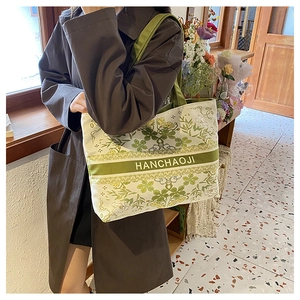 Gros plan détaillé du sac cabas en toile ivoire avec motifs floraux verts et logo