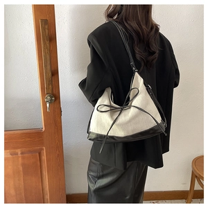 Detail of colorblock canvas tote bag with leather trim and decorative bow knot detail