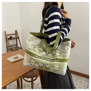 Détail du sac cabas en toile avec imprimé floral vert et sangle à logo élégant
