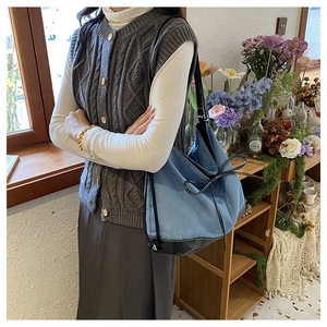 Blue denim contrast tote bag styled with a grey vest and pleated skirt for a casual look
