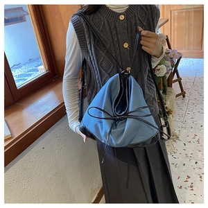 Close-up of vintage denim and black leather patchwork tote with decorative bow detailing