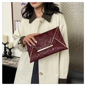 Close-up of wine red snake pattern envelope clutch with elegant gold metal bar detail