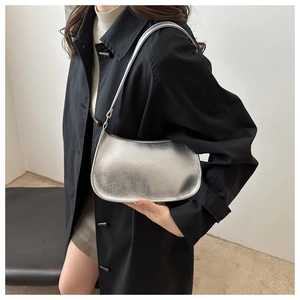 Sac baguette argenté métallique avec texture vintage porté à l'épaule par un mannequin