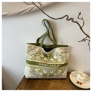 Grand sac cabas en toile à imprimé floral avec des poignées vert forêt sur une table
