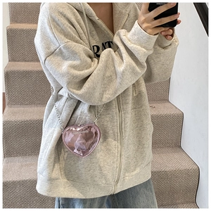Detail of a mini heart-shaped metallic purple crossbody bag with chain on a soft grey sweater