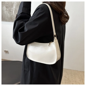 Vue latérale du sac hobo en cuir verni crème porté par un mannequin sur un manteau