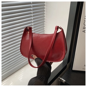 Détail du sac baguette rouge avec texture plissée brillante et finitions dorées