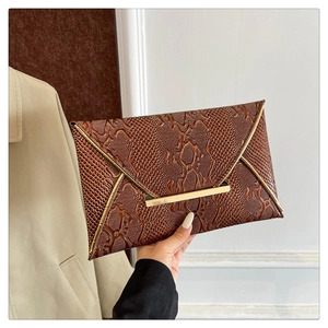 Detail of dark brown snakeskin embossed envelope clutch with elegant gold metal lock