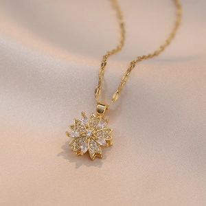 Elegant rotating zircon flower pendant necklace in gold finish on silk background
