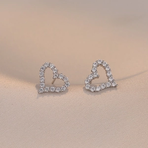 Elegant silver heart stud earrings with sparkling pavé cubic zirconia on silk fabric
