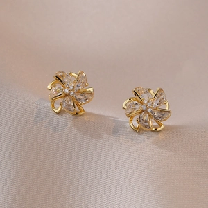 Rotating zircon windmill stud earrings in gold plating on elegant silk background