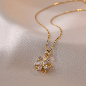 Golden rotating windmill necklace with sparkling crystals on silk background