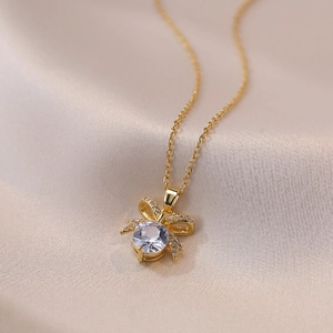 Elegant gold bow necklace with a large round zircon pendant on champagne silk fabric