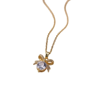 Minimalist gold necklace featuring a bow pendant with a large sparkling round zircon crystal