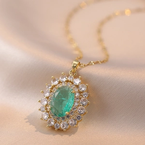 Elegant gold necklace with a large oval emerald gemstone pendant surrounded by white zircons