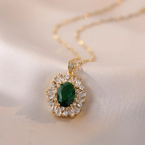 Elegant gold necklace with oval emerald pendant surrounded by clear zircons on silk