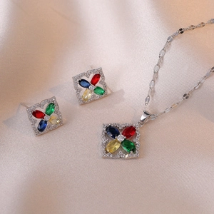 Exquisite silver necklace and earrings set with four-color gemstones on champagne silk fabric