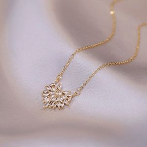 Elegant gold heart pendant necklace with zircon floral motif on gray silk fabric