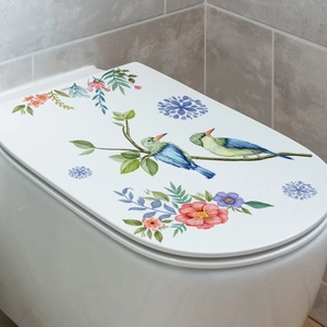 Detailed view of floral wall sticker with birds on a white toilet lid in a gray bathroom