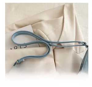 Detail view of the wide comfortable shoulder strap and silver zipper on this light blue tote