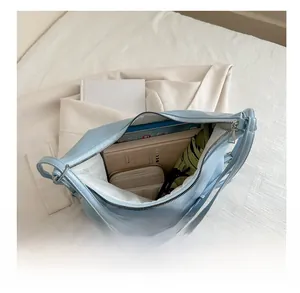 Detailed interior of light blue shoulder bag showing spacious storage for wallet and notes
