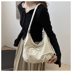 Close-up of cream white glossy finish hobo bag with delicate bow knot detailing