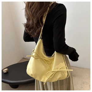 Pale yellow hobo bag with sweet ribbon details shown worn over the shoulder as a chic tote