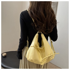 Detail of light yellow patent leather shoulder bag with a large decorative bow