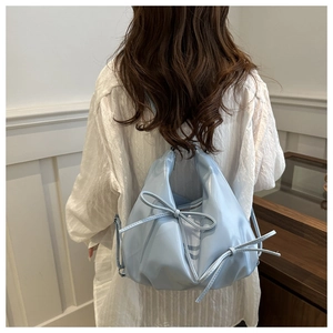 Detail of light blue glossy bow handbag featuring cloud pleats and metallic zipper