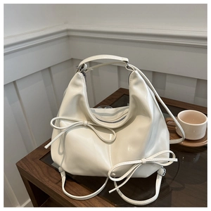 Detail of a creamy white moon-shaped hobo bag featuring bow knot ribbons and smooth texture