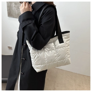 Sac fourre-tout matelassé blanc perle métallisé avec bandoulières noires porté à l'épaule