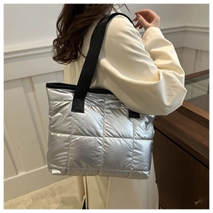Détail du grand sac cabas argenté matelassé avec bandoulière noire porté par mannequin