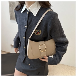 Minimalist beige leather underarm bag with gold buckle shown on a model