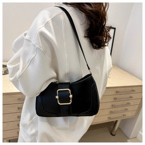 Detail of a chic black leather underarm bag featuring a bold gold square buckle accent