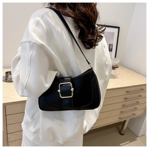 Detailed side view of black leather underarm bag with gold buckle on model