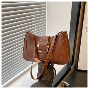 Macro shot of brown retro underarm bag featuring a metallic gold buckle closure detail
