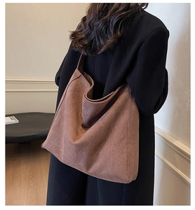 Détail d'un grand sac cabas en daim marron avec texture souple et large bandoulière