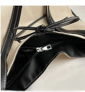 Detail of smooth zipper closure on contrast canvas tote with leather trim and stitching