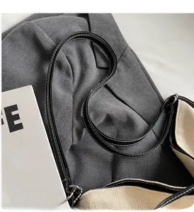 Detail of off-white canvas tote bag featuring black leather trim and contrast stitching