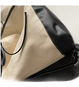 Detail of herringbone canvas fabric with black leather trim and white contrast stitching