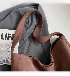 Vue détaillée du sac cabas en daim marron avec poignées larges renforcées et fini mat