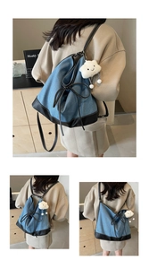 Detail view of denim canvas backpack with leather patchwork and white cloud plush charm