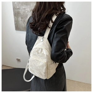 Detailed view of white pleated PU leather backpack with silver zippers and mini shoulder straps