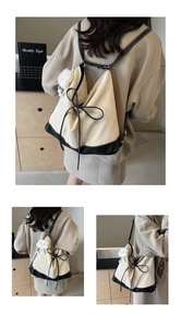 Detail of beige herringbone backpack with black leather straps and plush cloud charm