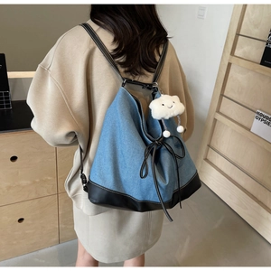 Detail of denim patchwork backpack with black bow accent and fluffy cloud charm pendant