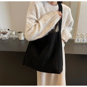 Grand sac cabas noir minimaliste porté par un mannequin avec bandoulière souple et chic
