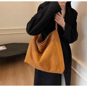 Détail de la texture en daim marron doux et de la bandoulière sur un grand sac cabas
