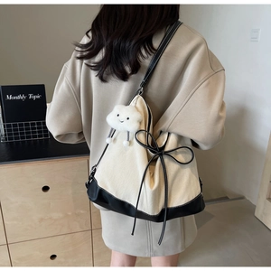 Side view of a canvas tote bag with black bow and cute cloud charm on shoulder
