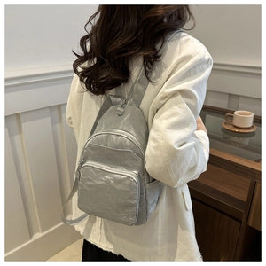 Silver-grey wrinkled nylon backpack detail showing glossy texture on model