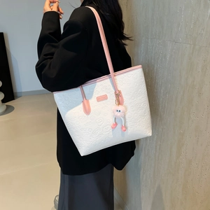 Sac cabas crème chic avec motifs en relief et détails roses porté par un mannequin en automne